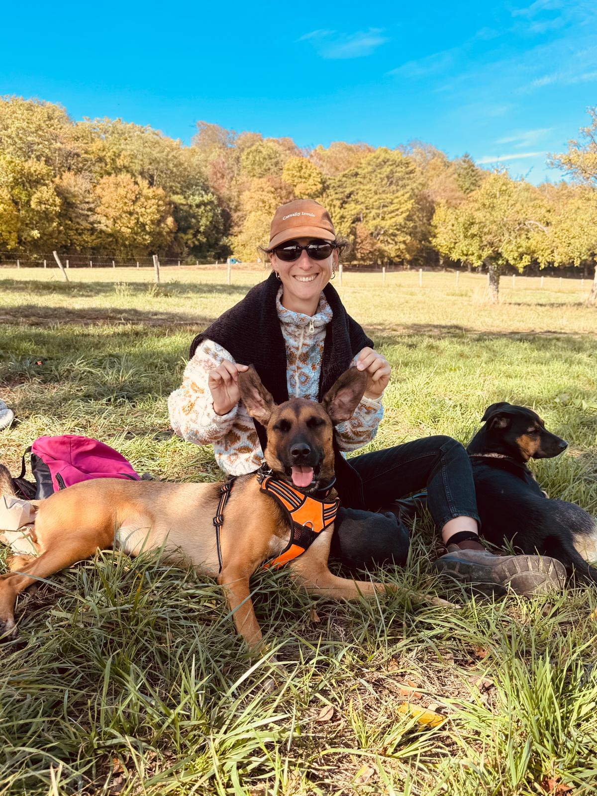 Océane souriante avec deux chiens dans un pré